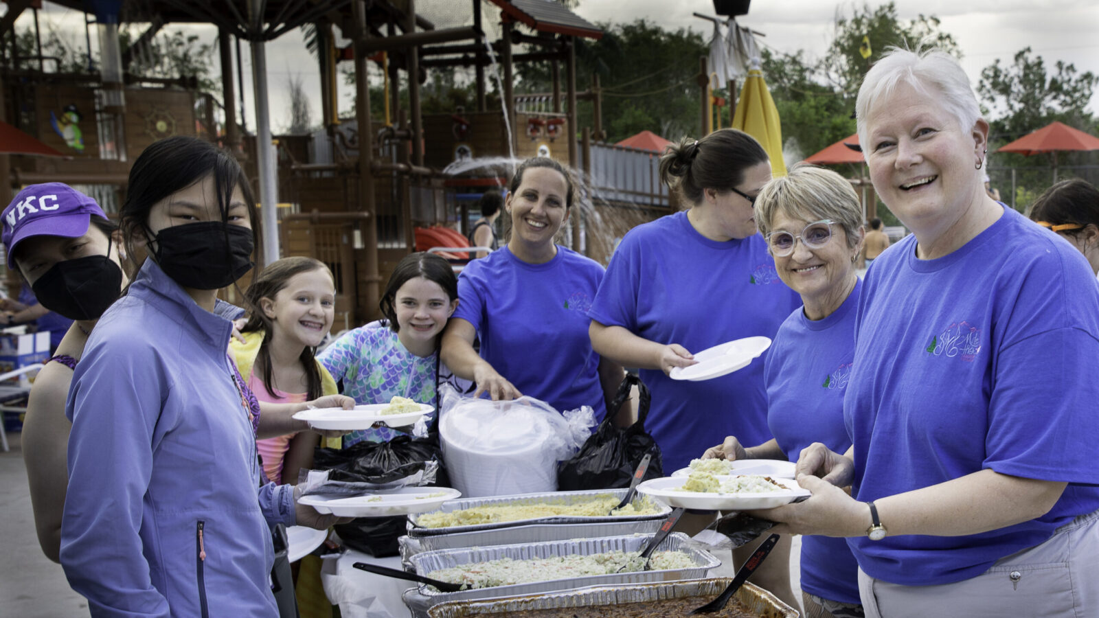 Picture of people smiling as they get food at a buffet